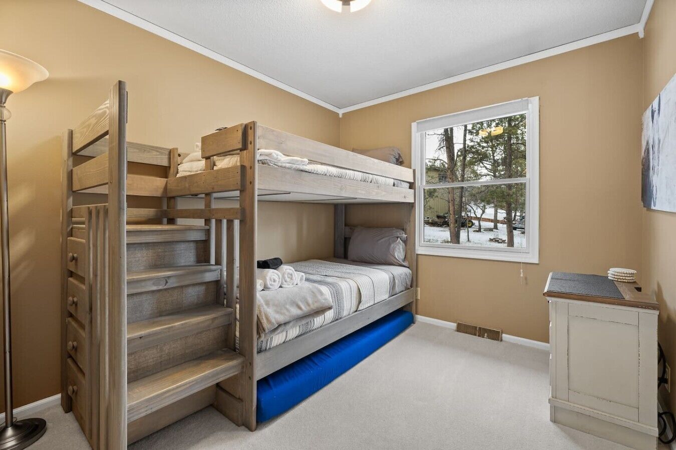 A bunk bed room with a window, a desk, and a lamp.