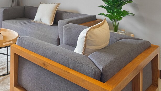 A modern living room with a grey sofa set, wooden frame, and a small wooden side table. - Hanae by Kozystay - Kuningan (Jakarta)