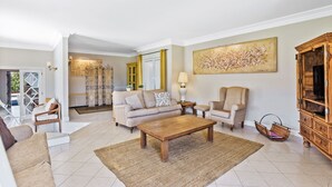 Ein geräumiges Wohnzimmer mit einem beigen Sofa, einem Holztisch und einem großen abstrakten Gemälde an der Wand.