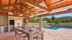 Eine Terrasse im Freien mit einem Esstisch für zwei Personen, einer Steinmauer und einem Poolbereich.