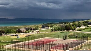 Ein Basketballplatz mit roter Oberfläche, umgeben von einem schwarzen Zaun, mit Häusern im Hintergrund.