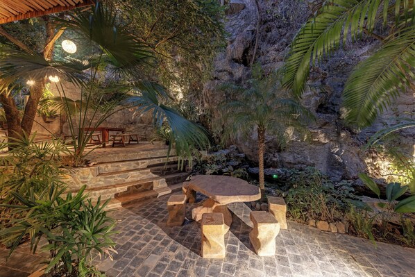 An outdoor patio with stone seating and steps leading to a stone wall.