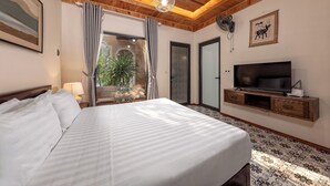 A hotel room with a bed, a television, a fan, and a view of the outdoors. - Trang An Aroma Homestay (Ninh Binh)