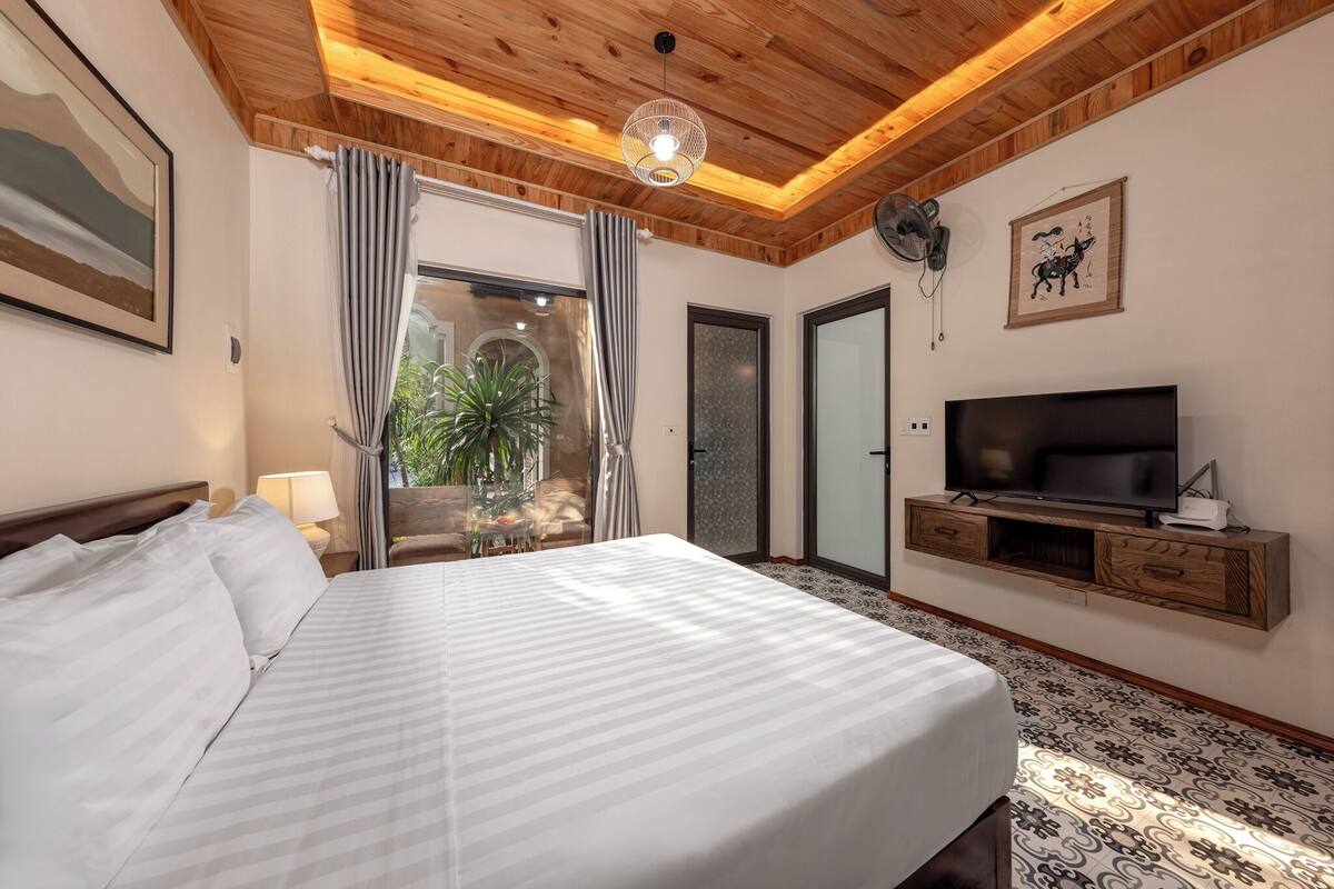 Una camera d'albergo con un letto, una televisione, un ventilatore e vista sull'esterno.