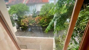Vista dalla finestra su un giardino e un edificio con tetti rossi.