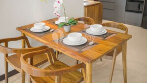 Una mesa de comedor de madera con platos, tazones y una orquídea en maceta.