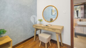 Un baño moderno con tocador de madera, espejo redondo y pequeño taburete.