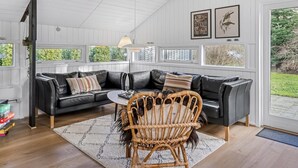 A cozy living room with a black leather sectional sofa, a wicker chair, and a dining table. - "Reino" - 30km from the sea by Interhome (Toftlund)