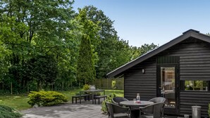 A patio area with a table and chairs, surrounded by a garden with trees and shrubs. - "Reino" - 30km from the sea by Interhome (Toftlund)