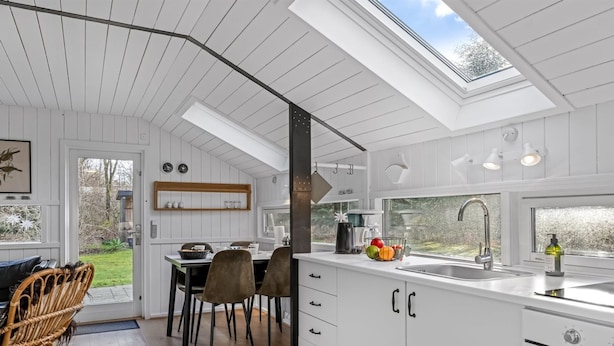 A modern kitchen with white cabinetry, a large island, a skylight, and a view of the outdoors. - "Reino" - 30km from the sea by Interhome (Toftlund)