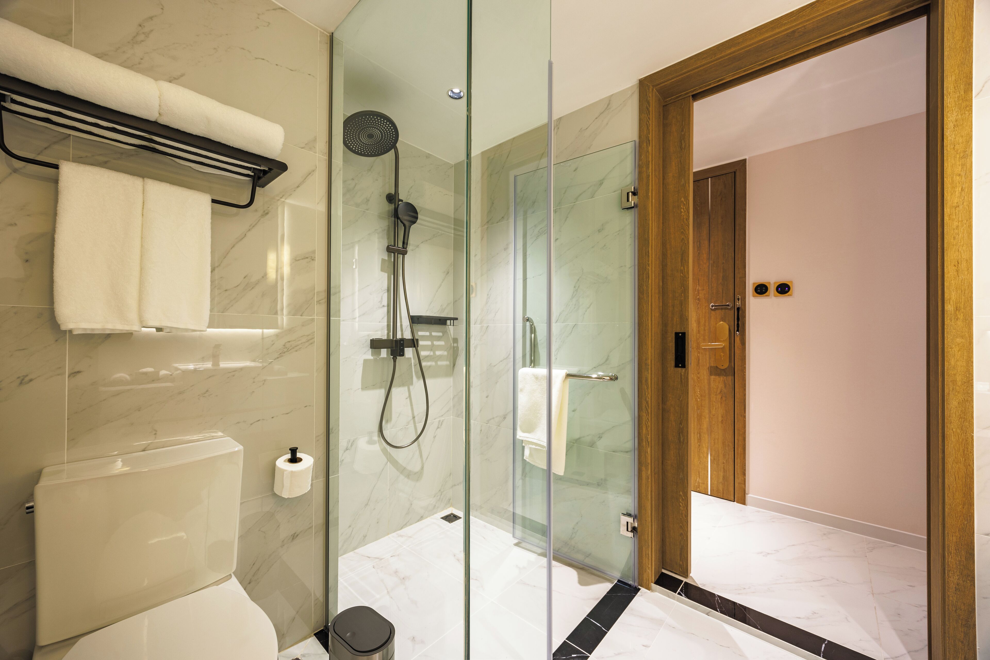 Une salle de bain moderne avec une douche à parois de verre, des toilettes et un porte-serviettes.