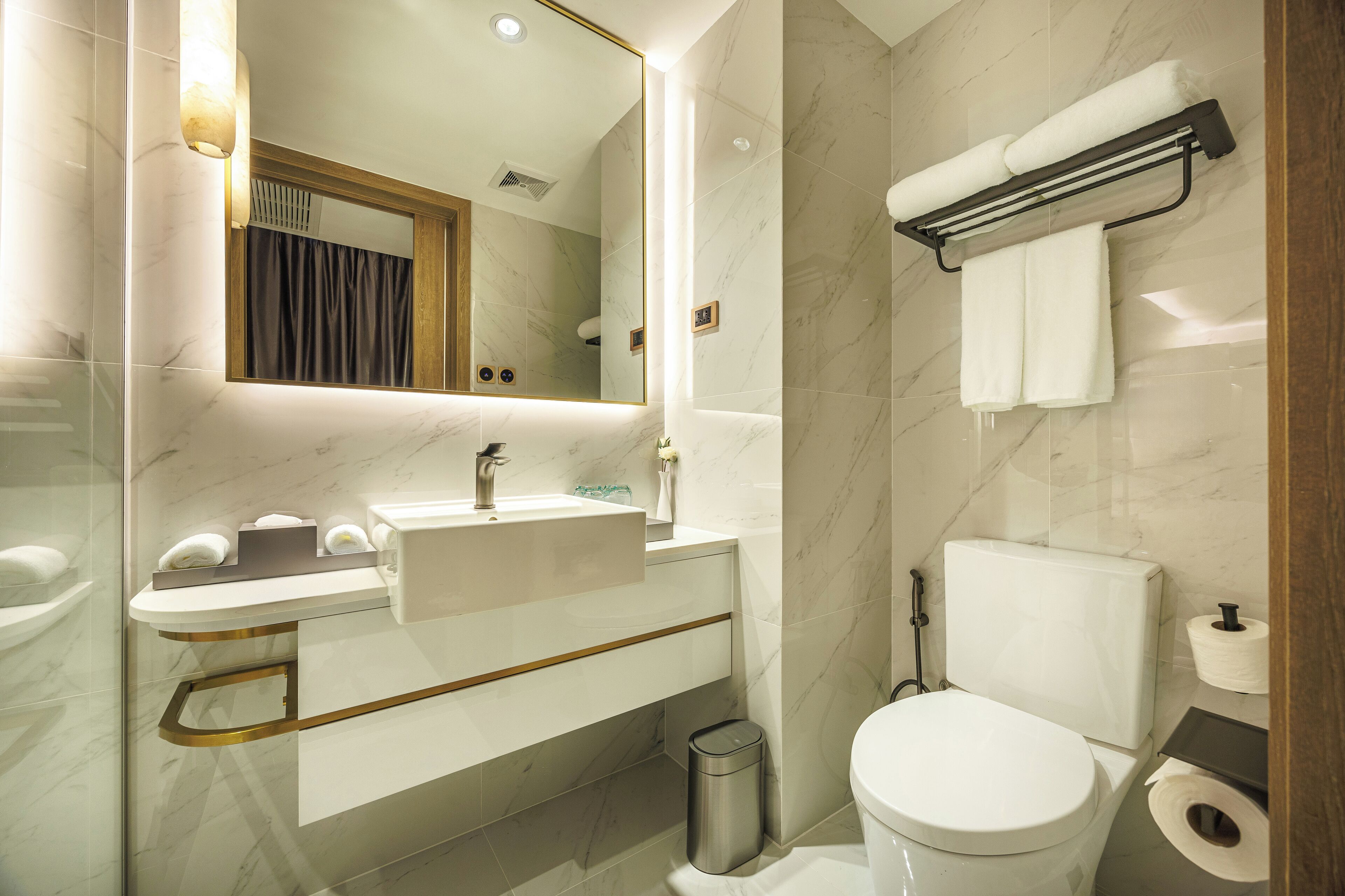 A modern bathroom with a marble sink, a toilet, and a towel rack.
