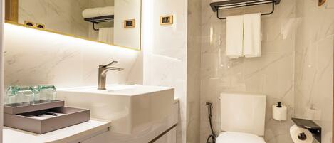 A modern bathroom with a marble floor, a large mirror, a white sink, and a toilet.