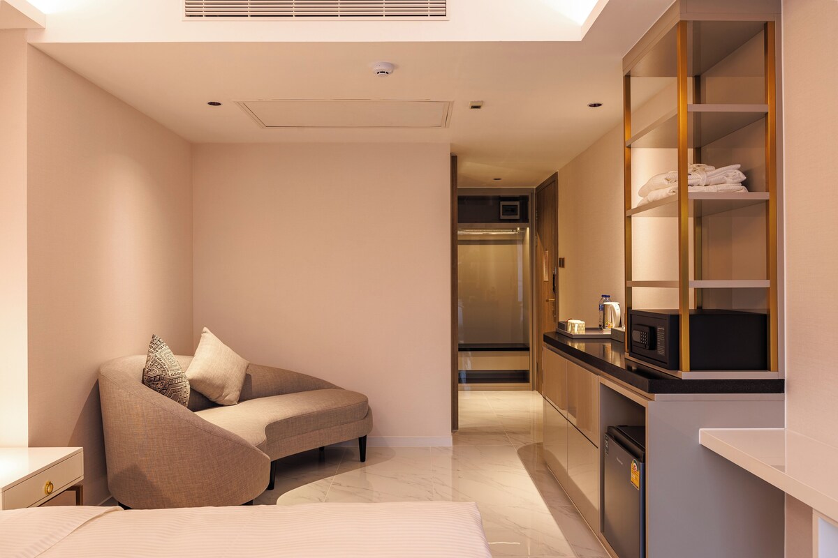 Una habitación de hotel moderna con sofá, cama, kitchenette y armario empotrado.