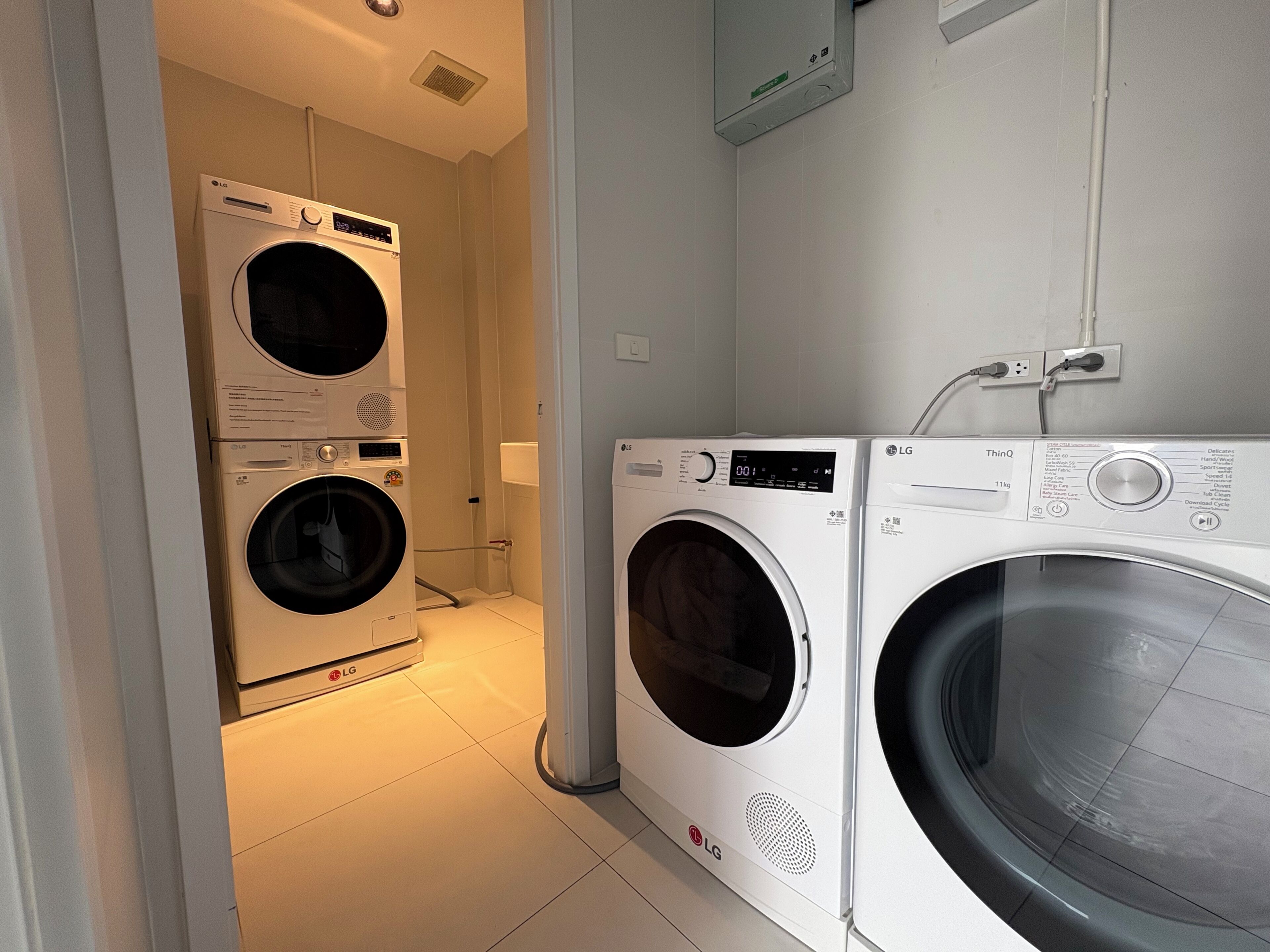 Une buanderie équipée de deux lave-linge LG superposés et d’un seul sèche-linge LG.