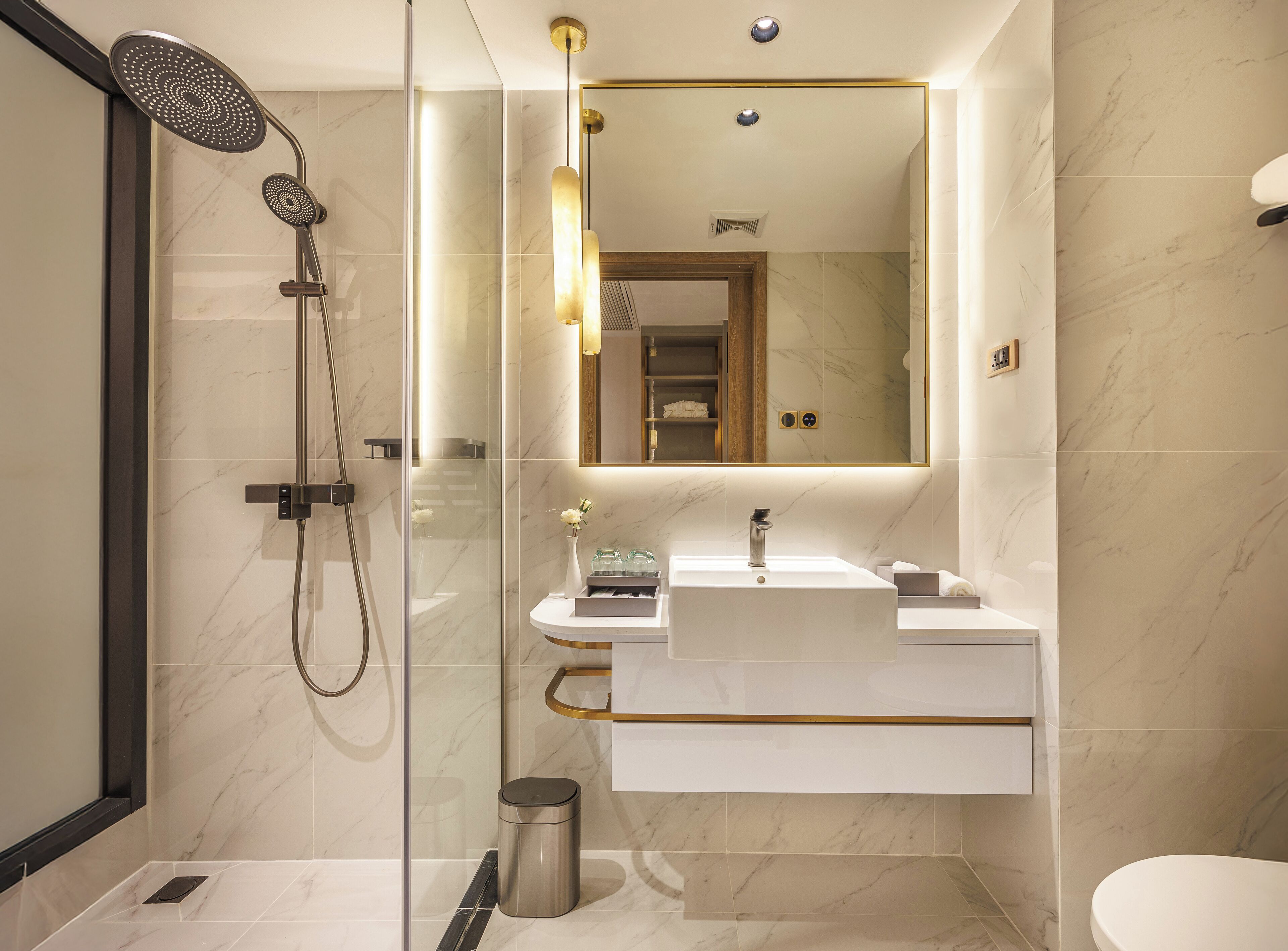 A modern bathroom with a glass-enclosed shower, a vanity with a sink, and a large mirror.