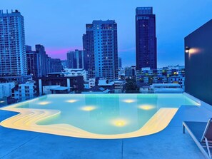 Ein Pool auf dem Dach mit Blick auf die Stadt, umgeben von Hochhäusern.