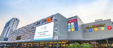 A modern building with a unique geometric facade, a large billboard, and multiple flags indicating various brands.