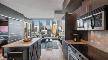 A modern kitchen with a city view, a dining area, and a living space.