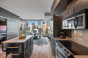 A modern kitchen with a city view, a dining area, and a living space. - King Bed | Calgary Tower Views |Walk to Saddledome (Calgary)