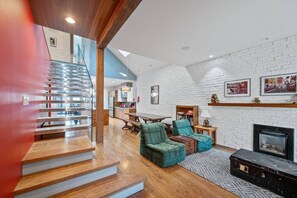 Un interior moderno con escalera, zona de estar, chimenea y paredes de ladrillo blanco.