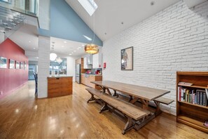 Un interior moderno con una mesa de comedor de madera, una pared de ladrillo blanco y una estantería.