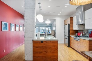 Una cocina moderna con una isla central, electrodomésticos de acero inoxidable y una pared de acento roja.