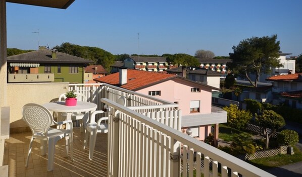 A balcony with a table and chairs, overlooking a residential area with various buildings.