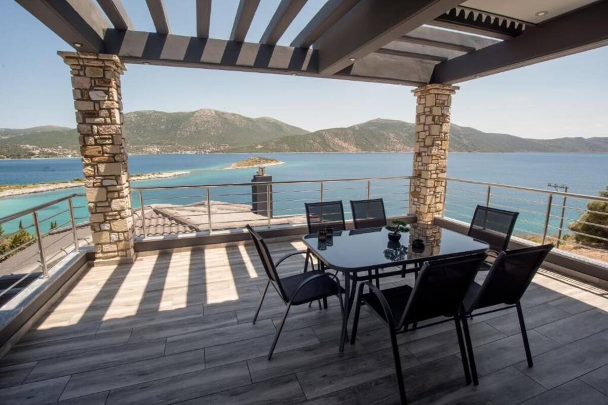 A covered outdoor dining area with a view of the sea and mountains.