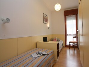 Cozy retreat with a single bed, bedside table, and plush chair, perfect for a relaxing stay.