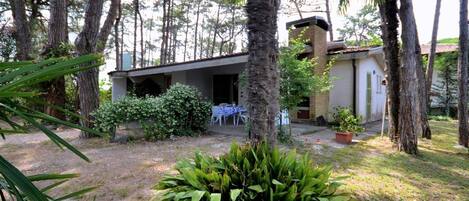 Un edificio con un patio cubierto, rodeado de árboles y follaje.