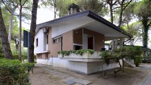 Ein modernes Haus mit flachem Dach, einer kleinen Veranda und einem Garten.
