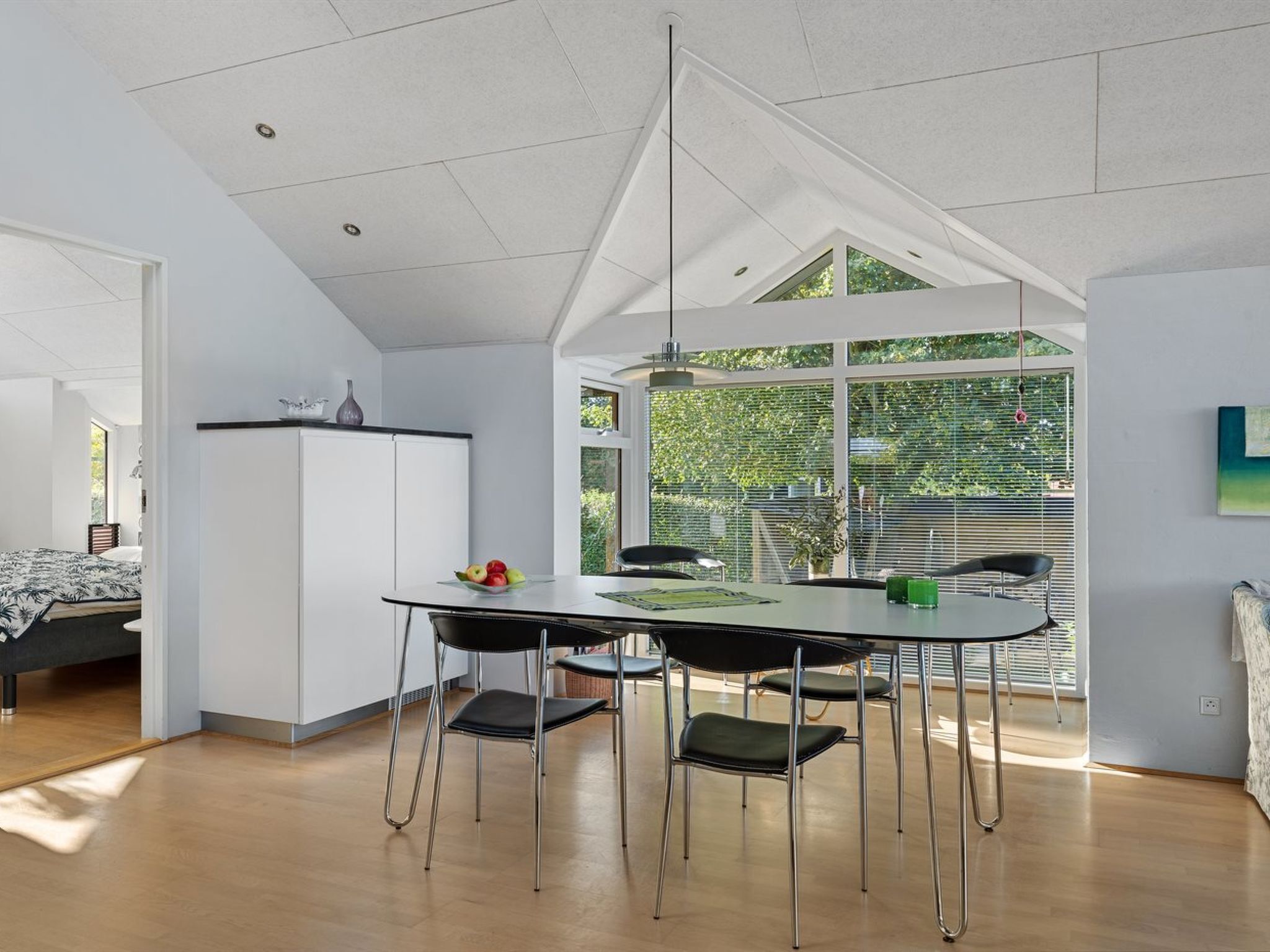Cocina moderna con zona de comedor, techo blanco, ventanas amplias y vistas a zonas verdes.