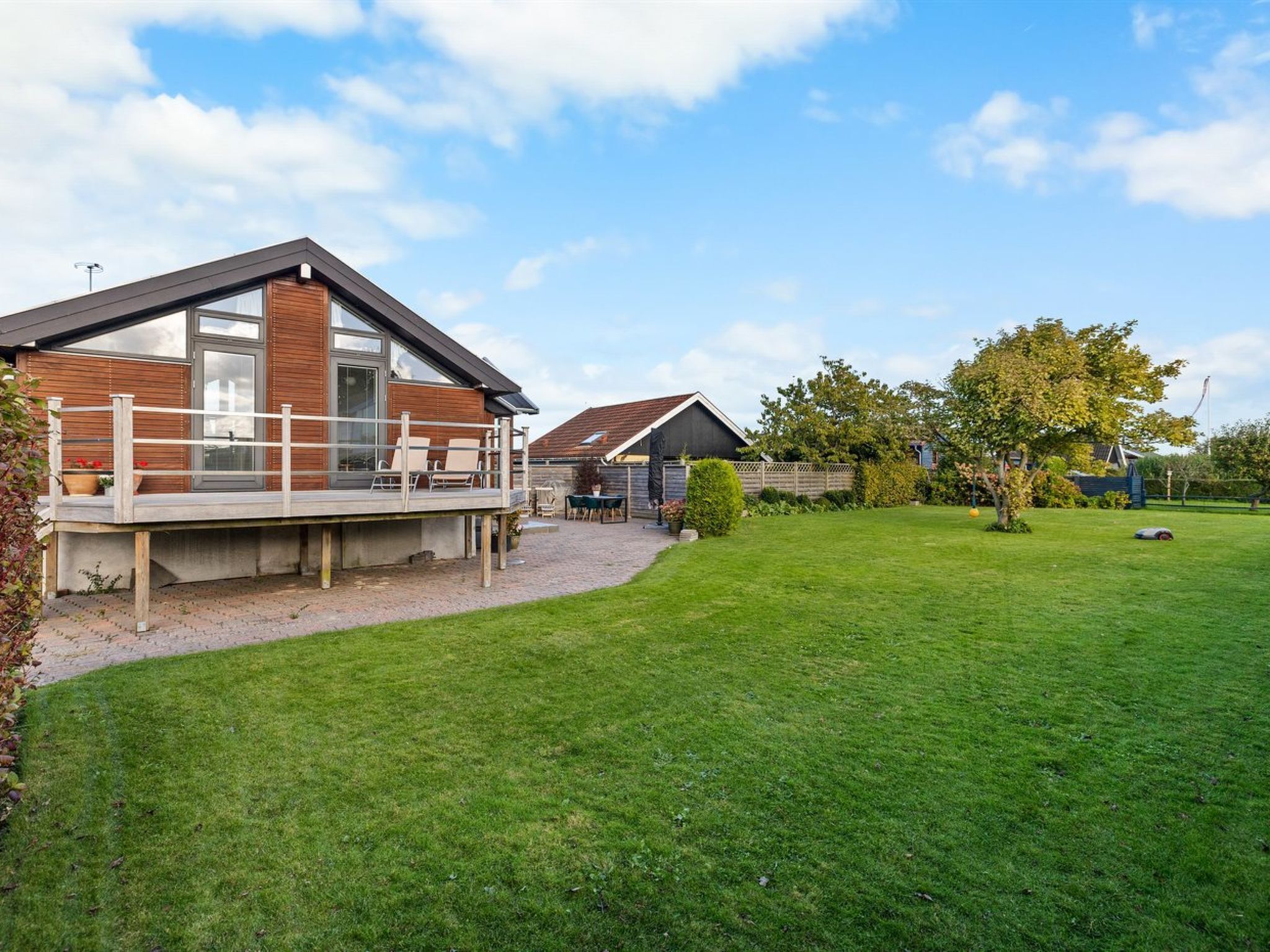 A modern house with a deck, a well-maintained lawn, and a clear sky.