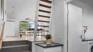 Une cuisine moderne dotée d’un lave-linge encastré, d’un escalier menant à un espace extérieur et d’une petite plante en pot posée sur un plan de travail.