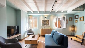 Un salon comprenant un téléviseur, un canapé, un fauteuil, une table basse et une lampe.