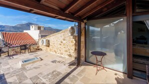 A covered outdoor area with stone walls, a table, chairs, and an air conditioning unit.