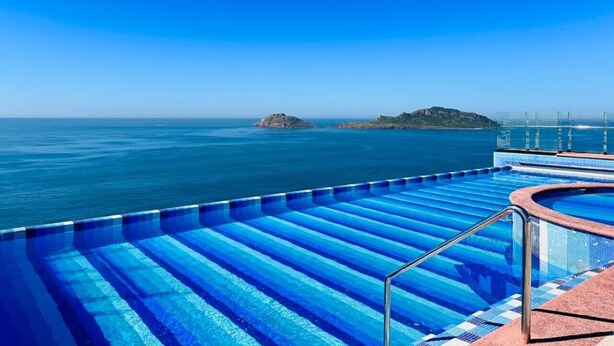 Uma piscina com vista desobstruída do oceano e uma ilha ao longe.