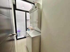 Bathroom features a stainless steel door, white sink, and small window for natural light.