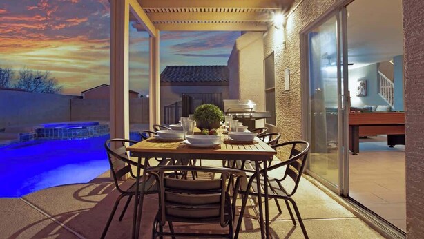 An outdoor dining area with a pool, a pergola, and a view of the backyard. - Rare 6BR Gem w/ Pickleball, Pool, & Arcade in NLV (North Las Vegas)