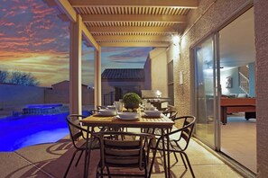Een eethoek buiten met een zwembad, een pergola en uitzicht op de achtertuin.