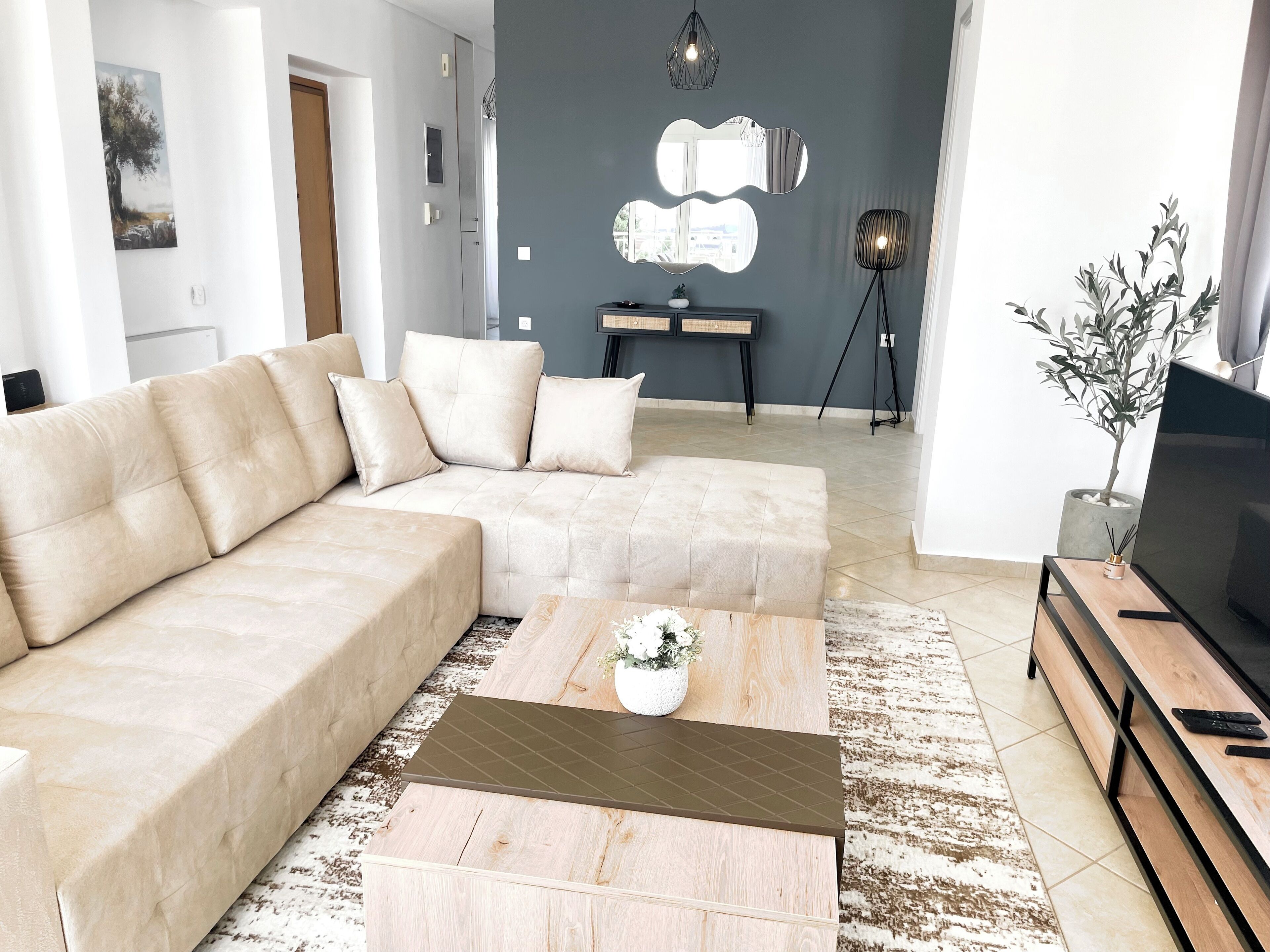 Een moderne woonkamer met een beige hoekbank, een houten salontafel en een tv op een houten dressoir.