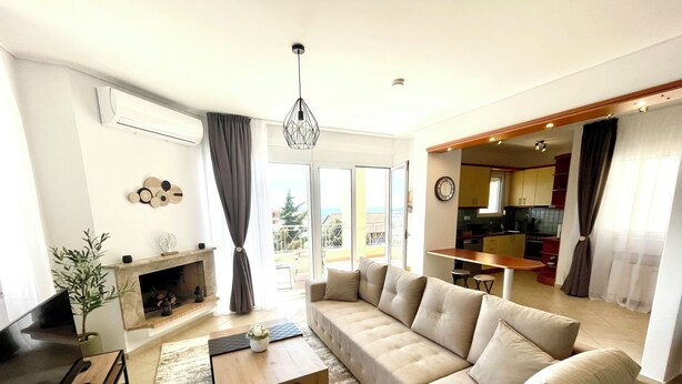 Una sala moderna con un sofá seccional, una chimenea y vistas a la cocina y al balcón.