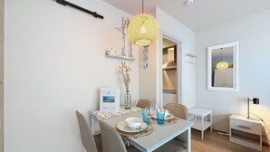 Comedor con una mesa dispuesta para cuatro, una lámpara colgante y un espejo en la pared.
