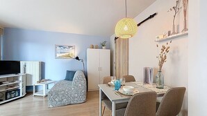 Una sala de estar moderna con sofá, mesa de comedor y televisor.