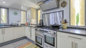 A modern kitchen with white cabinets, stainless steel appliances, a gas stove, and a large window. - Beautiful private villa for 6 people with WIFI and TV (Invermoriston)