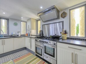 A modern kitchen with white cabinets, stainless steel appliances, a gas stove, and a large window.