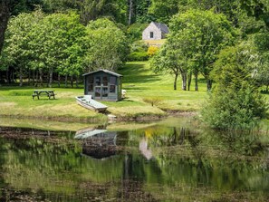 Un chalet au bord du lac, doté d’un quai, et entouré d’une végétation luxuriante et d’arbres.