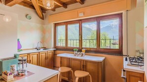 Une cuisine avec des meubles en bois, une grande fenêtre et une vue sur les montagnes.