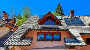 A house with a sloped roof, solar panels, and a window with a mountain view.